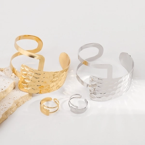 Dettaglio del set di bracciali a polsino geometrici e anelli martellati oro e argento