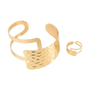 Dettaglio del set bracciale rigido e anello geometrici dorati con trama martellata