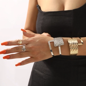 Set minimalista di bracciali e anelli martellati in oro e argento indossati da modella