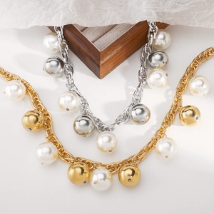 Gros plan détaillé de grosses perles et boules métalliques sur un collier à gros maillons
