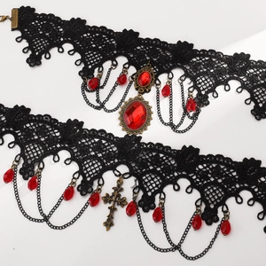 Close-up of gothic black lace chokers with red gemstones and bronze metal pendants