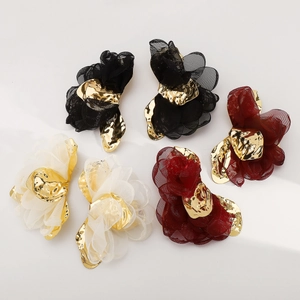 Detalle de pendientes de flores en tul y metal dorado en colores negro, blanco y rojo vino