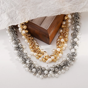 Detail view of gold and silver pearl necklaces placed on a vintage wooden jewelry box