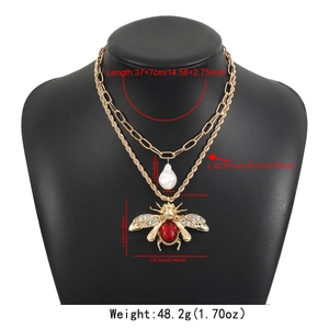 Detail view of gold insect necklace with red gemstone bee and white teardrop pearl