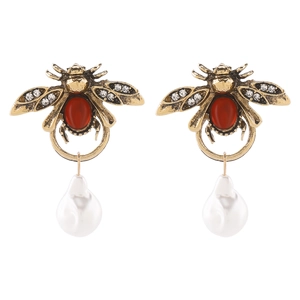 Detailed view of vintage gold bee earrings with red gemstones and baroque pearl drops
