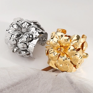 Makro-Detail von großen metallischen 3D-Blumen-Armreifen in glänzendem Gold und Silber