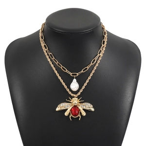 Close-up of vintage double-layer gold necklace with bee pendant and pearl drop detail
