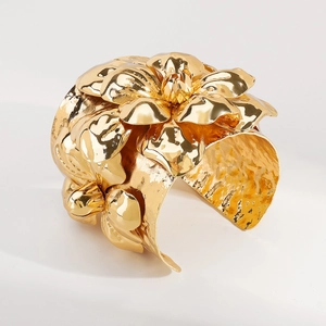 Detail eines breiten goldenen Armreifs mit 3D-Blumen und gehämmerter Metalloberfläche