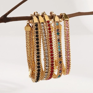 Détail de bracelets en zircon coloré sur des chaînes en acier inoxydable doré sur une branche