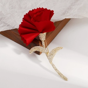 Macro detail of red fabric flower brooch with sparkling rhinestones on golden leaves