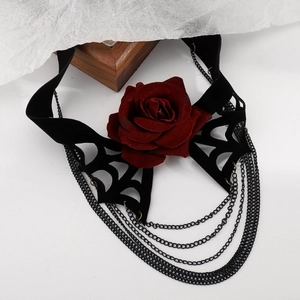 Détail macro de chaînes noires gothiques multicouches avec une rose en velours rouge foncé