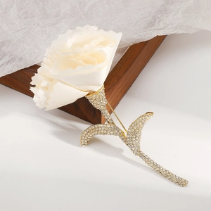 Detailed view of cream fabric flower brooch with shimmering crystal-set gold-tone stem