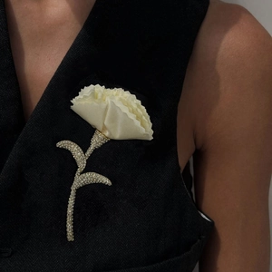 Elegant fabric flower brooch with shimmering rhinestones on a dark denim vest