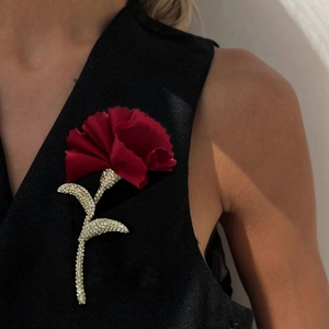 Elegant red fabric carnation flower brooch with sparkling diamond stem on black clothing