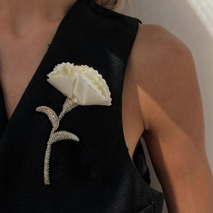 Elegant white fabric flower brooch with sparkling rhinestones on a black vest