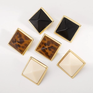 Primer plano de tres pares de pendientes de pirámide en negro, leopardo y crema