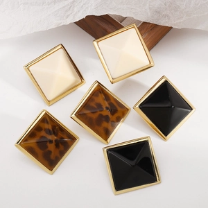 Primer plano de pendientes cuadrados en blanco crema, negro y estampado de leopardo