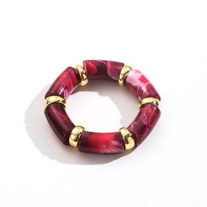 Detail view of burgundy marble texture resin tube bracelet with golden spherical spacers