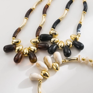 Detail view of bohemian acrylic beaded necklaces with gold metal tubes and teardrop pendants