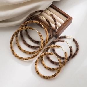 Detail of plush leopard print hoop earrings with textured faux fur and gold plated finish