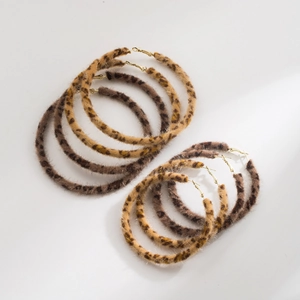 Macro shot of stylish plush leopard print hoop earrings with golden metal studs