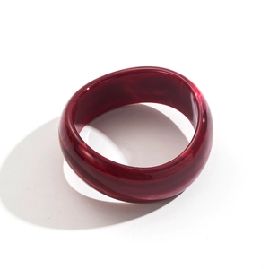 Macro view of wide resin bangle with deep red marble texture and polished finish