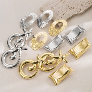 Macro view of geometric gold and silver metallic earrings with hammered textures