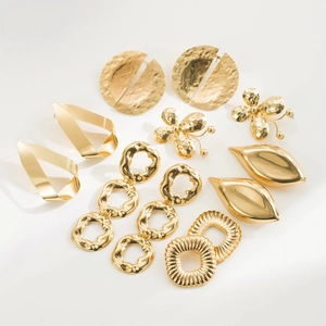 Vista macro de varios pendientes de metal dorado con texturas martilladas y pulidas