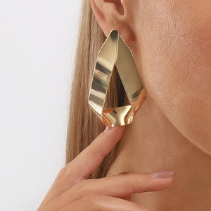 Pendientes geométricos dorados con diseño de torsión y acabado espejo en modelo