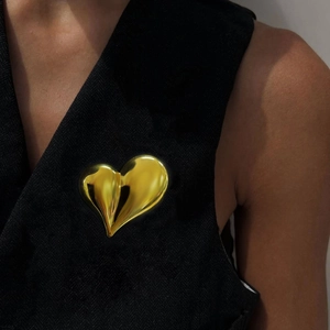 Broche cœur 3D minimaliste en acier doré épinglée sur le revers d'un costume noir