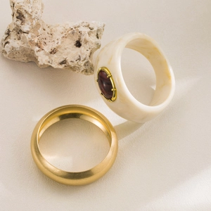 Close-up of vintage gold matte ring and ivory resin ring set on a natural stone base