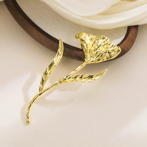 Elegant gold tulip brooch with textured hammered petals on white silk background