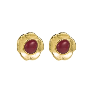 Gros plan de boucles d'oreilles dorées à bords ondulés et résine rouge centrale