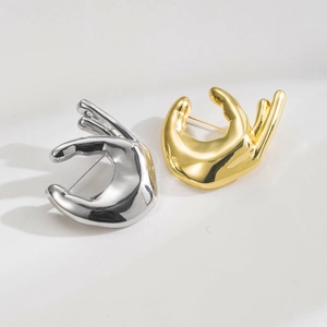Detailed view of hand gesture pins in polished gold and silver finish with metal butterfly clasp