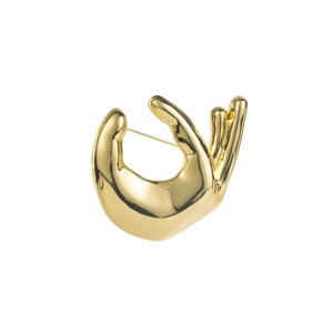 Macro detail of high-polish gold metal hand gesture brooch with secure pin back fastener