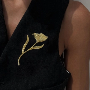 Vintage golden tulip flower brooch with hammered metal texture on black fabric vest