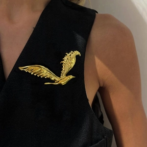 Broche d'aigle vintage dorée sur un gilet noir pour un style classique et élégant