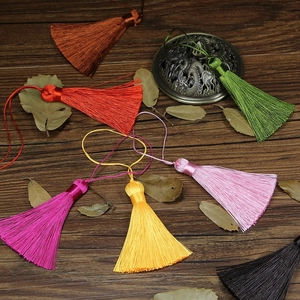 Detailed macro view of colorful handmade silk tassels arranged on dark wood texture