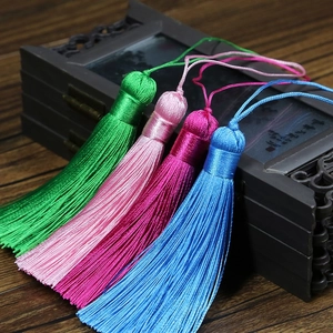 Detail of handmade silk tassels in green and pink on vintage carved wooden box