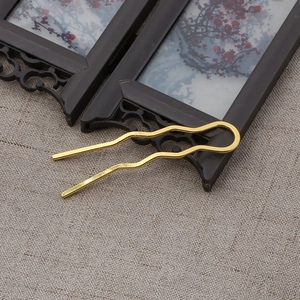 Gros plan d'une épingle à cheveux ondulée en métal doré sur un tissu en lin rustique