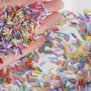 Mixed color bugle beads for DIY embroidery and jewelry making shown in hand close-up