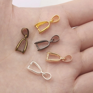 Five assorted metal pinch bails for pendants in gold silver and bronze on a hand palm