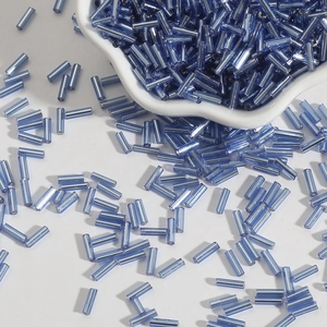 Light blue glass bugle beads in a ceramic bowl for DIY jewelry and hand embroidery