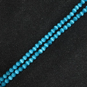 Close-up of light blue cat's eye round beads for DIY jewelry with distinct optical effect