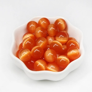 Polished orange cat eye beads for DIY jewelry making displayed in a white floral dish