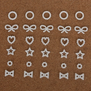 Detailed flat lay of white pearl ABS charms in bow heart and star shapes for DIY jewelry