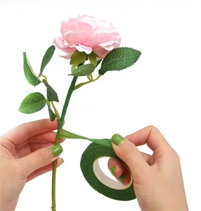 Close-up of dark green floral tape wrapping a pink rose stem for DIY flower arrangements