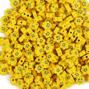 Macro view of yellow polymer clay flower beads with smiley faces for DIY jewelry making