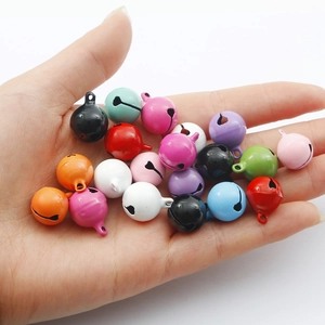 Hand hält bunte 14mm lackierte Eisen-Glöckchen für DIY-Schmuck und Bastelprojekte