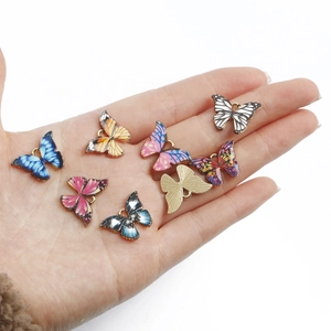 Bunte Schmetterlingsanhänger für DIY-Schmuck in verschiedenen Emaille-Stilen auf der Hand
